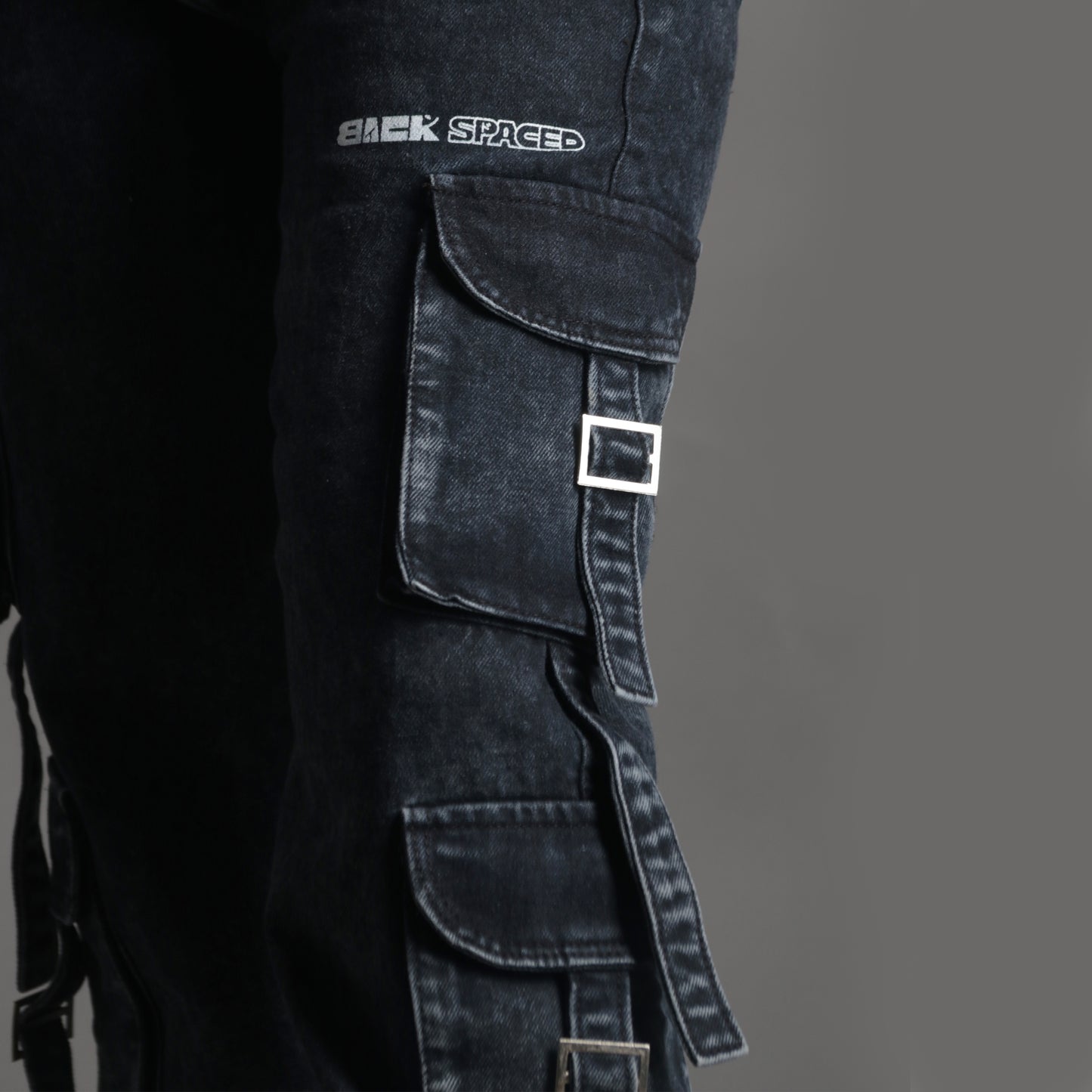 Close-up of side cargo pocket with stitching, flap details and the backspaced logo print on the charcoal cargo pants.